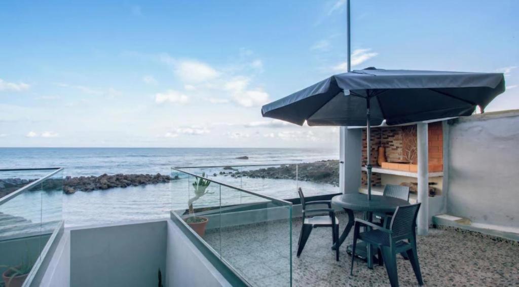a balcony with a table and chairs and an umbrella at Casa dos avós in São Vicente