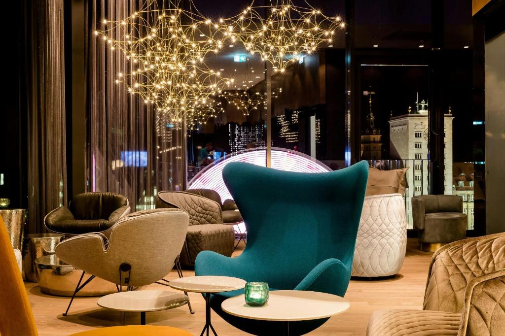 a room with chairs and tables and a chandelier at Motel One Leipzig-Post in Leipzig