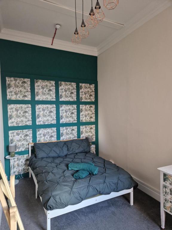 a bedroom with a bed with a green accent wall at Baile Apartment Central Inverness in Inverness