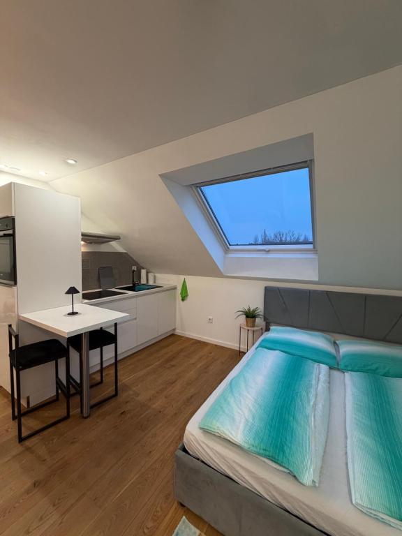 a bedroom with a bed and a kitchen with a window at Modernes Dachgeschoss in Augsburg