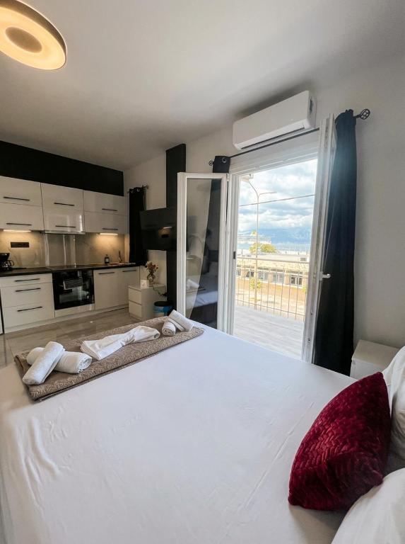 a bedroom with a large white bed with a large window at Mediterranean Port Suite in Ágios Rókkos