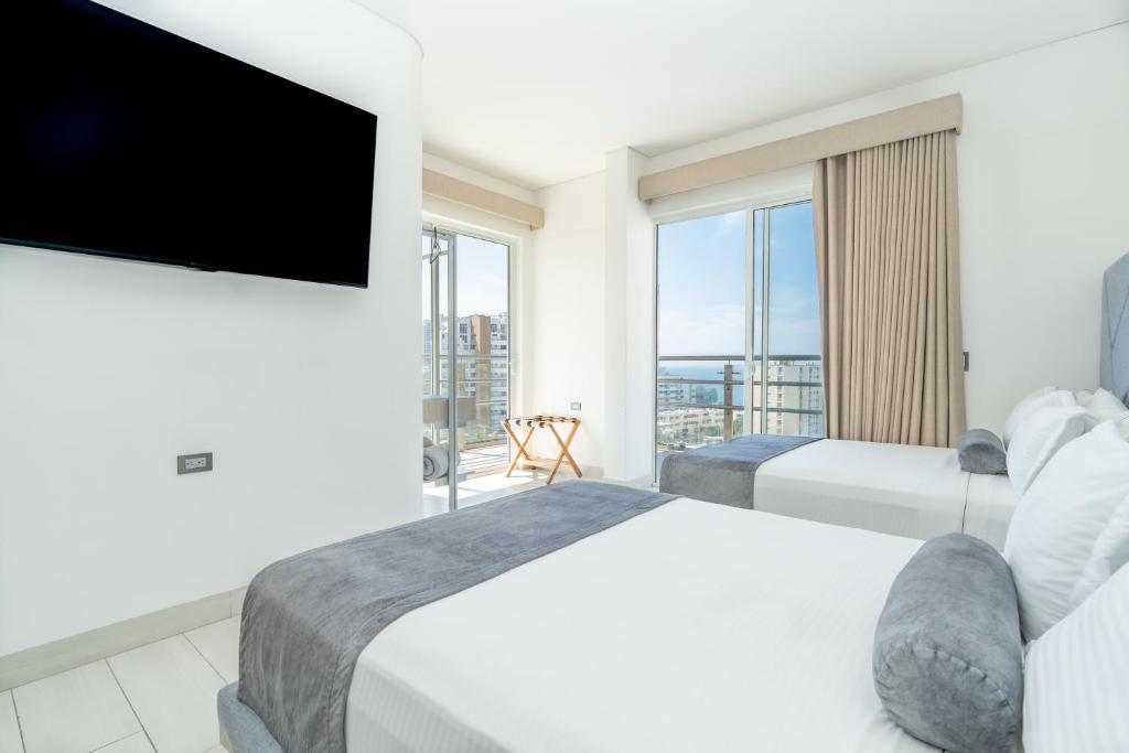 a bedroom with two beds and a flat screen tv at Hotel Marco Polo Rodadero in Santa Marta