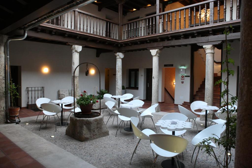 un patio con tavoli e sedie bianchi in un edificio di Evenia Alcalá Boutique Hotel ad Alcalá de Henares