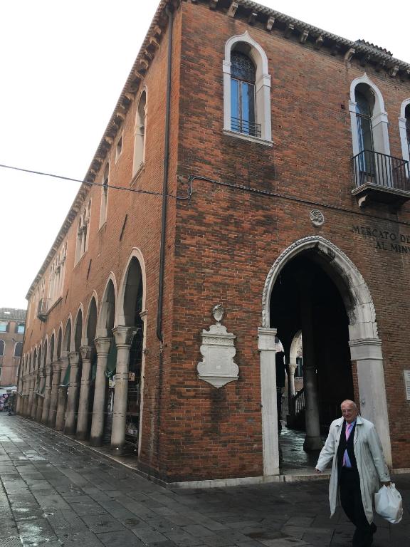 un hombre caminando delante de un edificio de ladrillo en Antico Mercato, en Venecia
