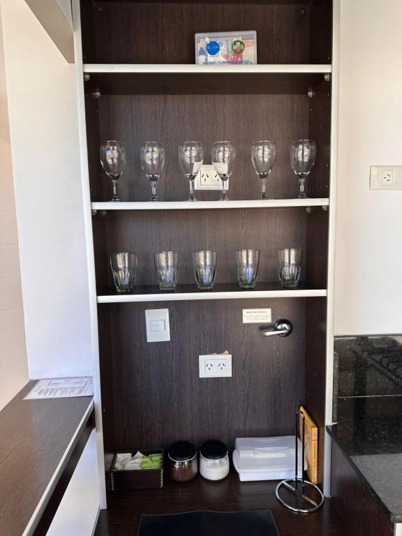 a row of wine glasses sitting on shelves in a kitchen at Apart Maral Zárate in Zárate
