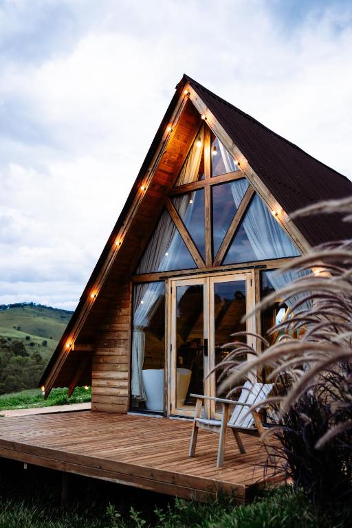 a wooden house with a large window on a deck at Olivas Eco Chalé in Pouso Alto
