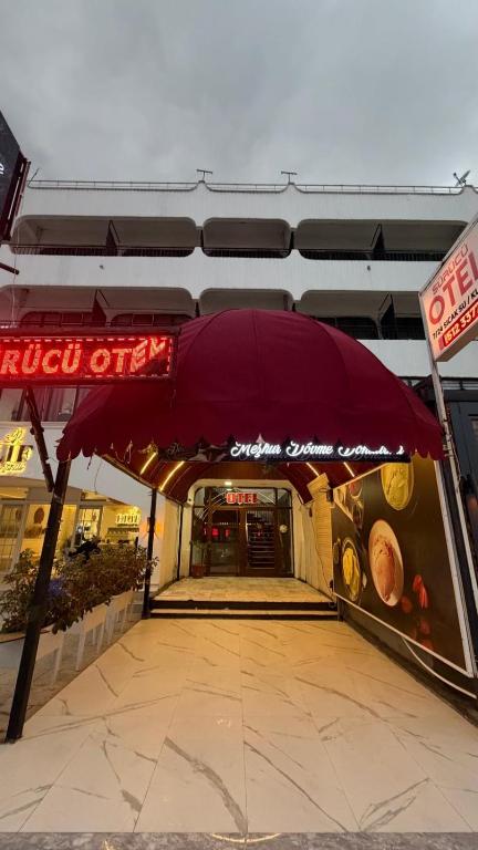 a restaurant with a red umbrella in front of a building at Sürücü oteli in Milas