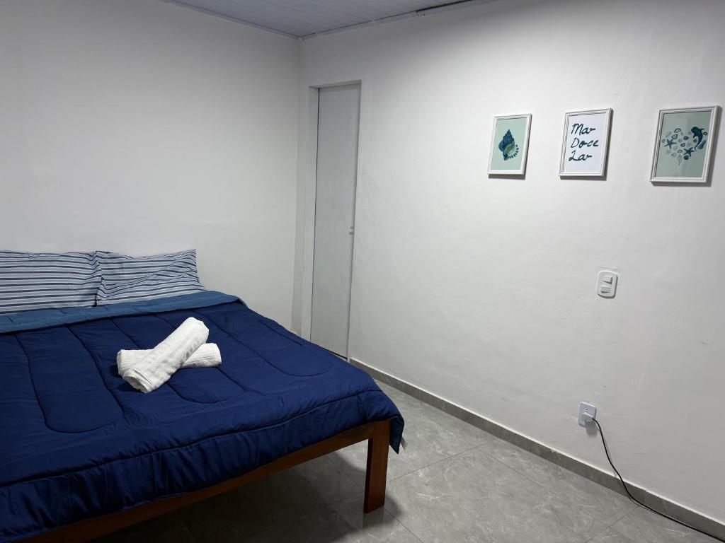 a bedroom with a bed with a blue blanket and paintings at Suíte Brisa Mar Saquarema in Saquarema