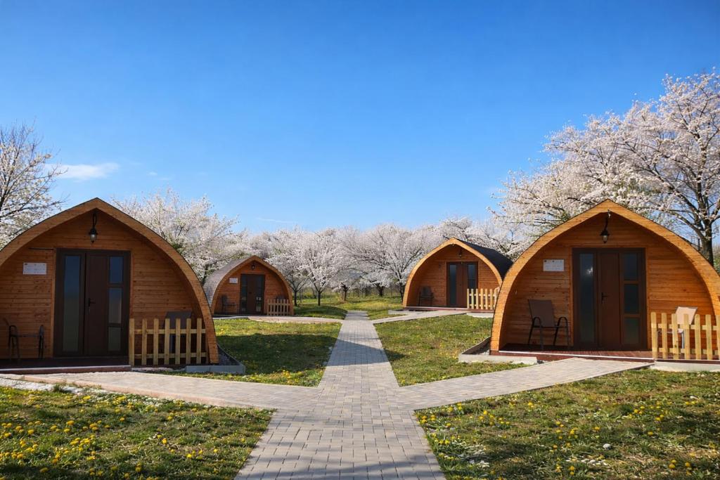 a row of wooden huts in a park with trees at Livada Luxurious Bungalow in Livada
