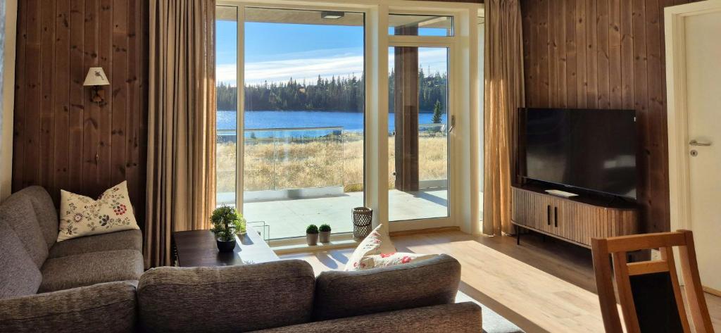 a living room with a couch and a large window at Flat With Lake View In Sjusjøen in Sjusjøen