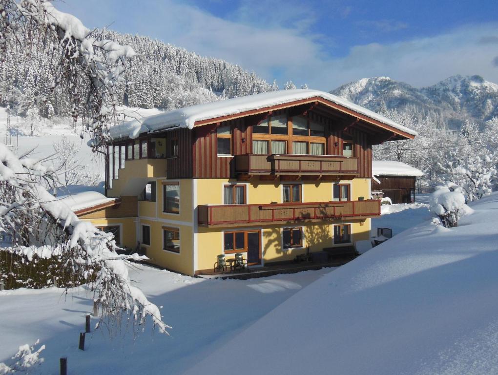 a large building in the snow with snow covered trees at Ferienwohnung Habel in Hochfilzen