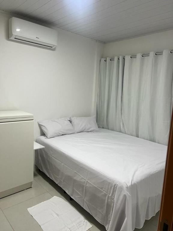 a small bedroom with a bed with white sheets at Carnaval 2026 in Tamandaré