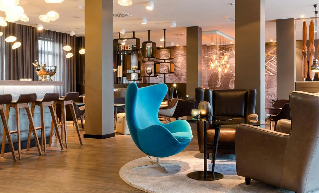 a restaurant with a blue chair and a table at Motel One Frankfurt-Airport in Frankfurt