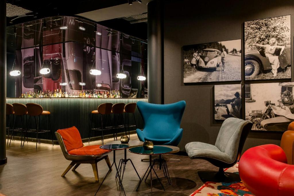 a waiting room with chairs and a bar with pictures at Motel One Frankfurt-East Side in Frankfurt