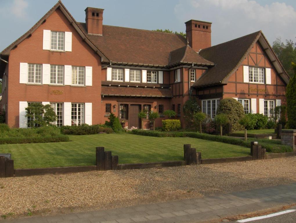 a large brick house with a lawn in front of it at Hotel Ten Lande in Beernem