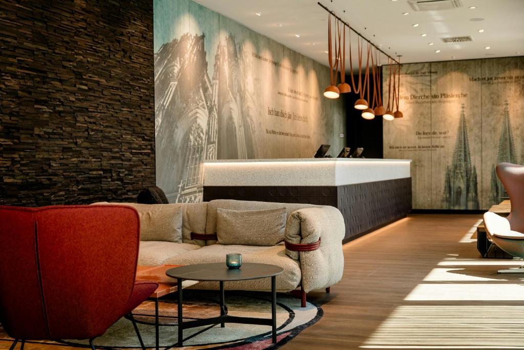 a living room with a couch and a table at Motel One Köln-Mediapark in Cologne