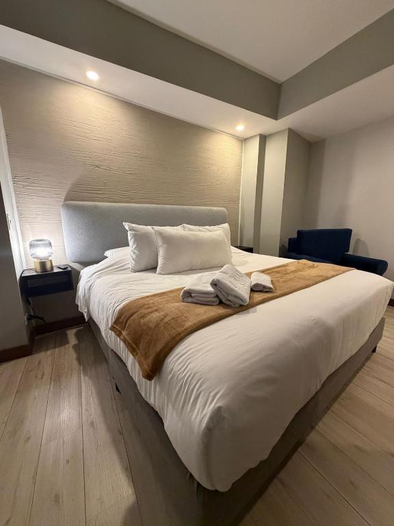 a bedroom with a large white bed with a brown blanket at CasaSue Living & Hotel in Bogotá