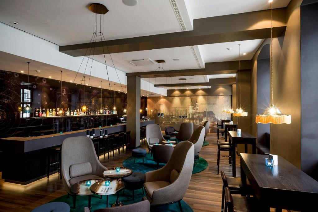 a restaurant with tables and chairs and a bar at Motel One Magdeburg in Magdeburg