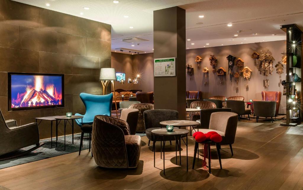 a lobby with a bar with chairs and tables at Motel One Freiburg in Freiburg im Breisgau