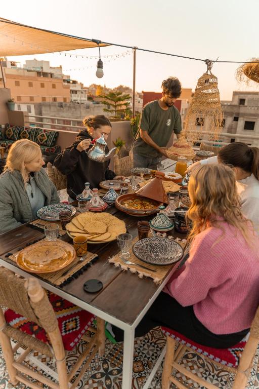 a group of people sitting around a table with food at taghoba surf house in Tamraght Ouzdar