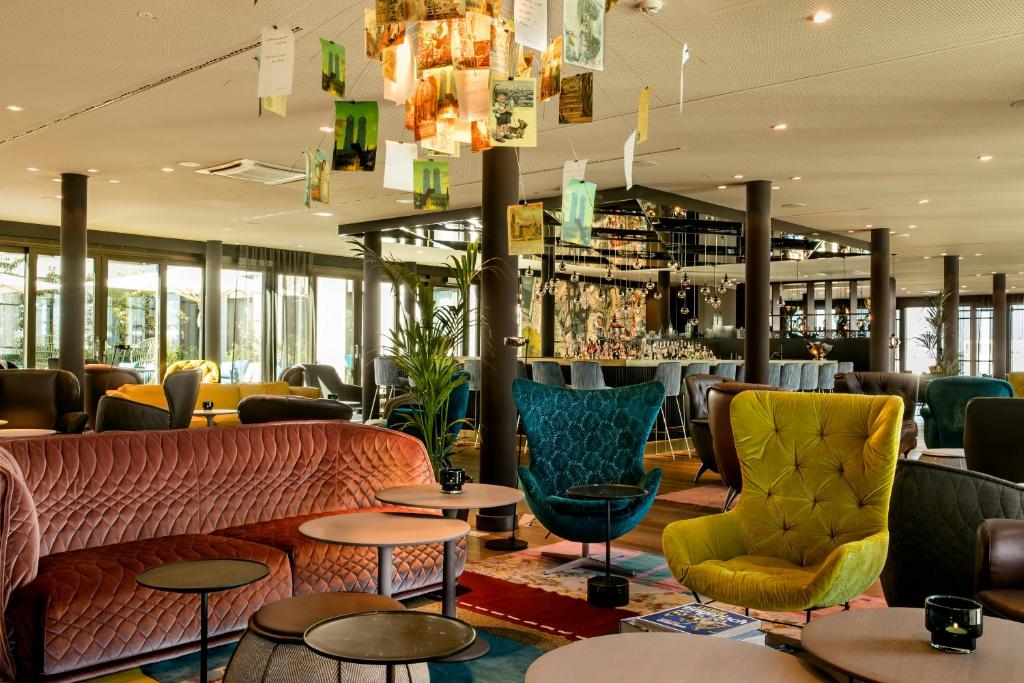 a restaurant with a couch and tables and chairs at Motel One München-Messe in Munich