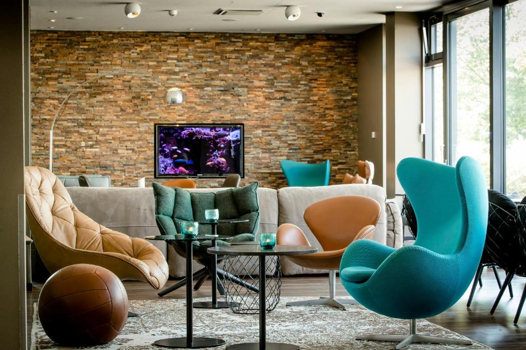 a living room with a couch and chairs and a brick wall at Motel One München-Garching in Garching bei München