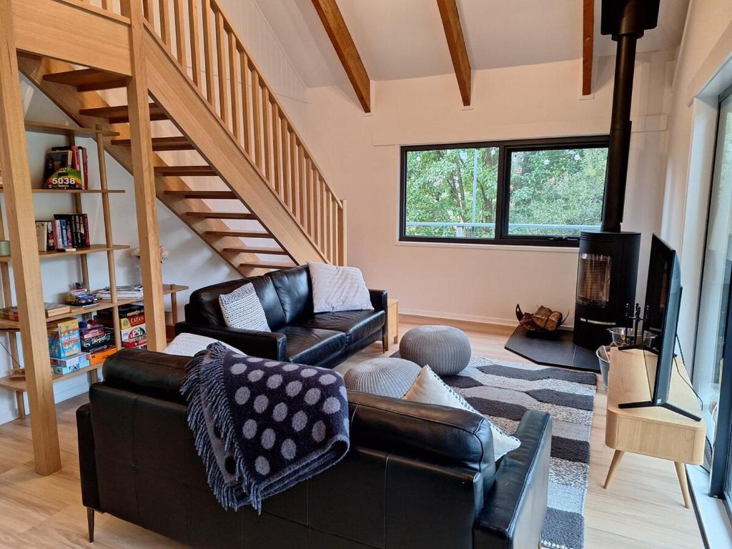 a living room with a leather couch and a television at Moonlight Ridge Chalet in Merrijig