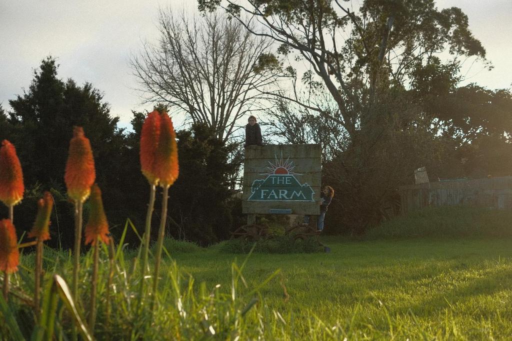 a sign for the farm in a field with flowers at The Farm in Whangaruru