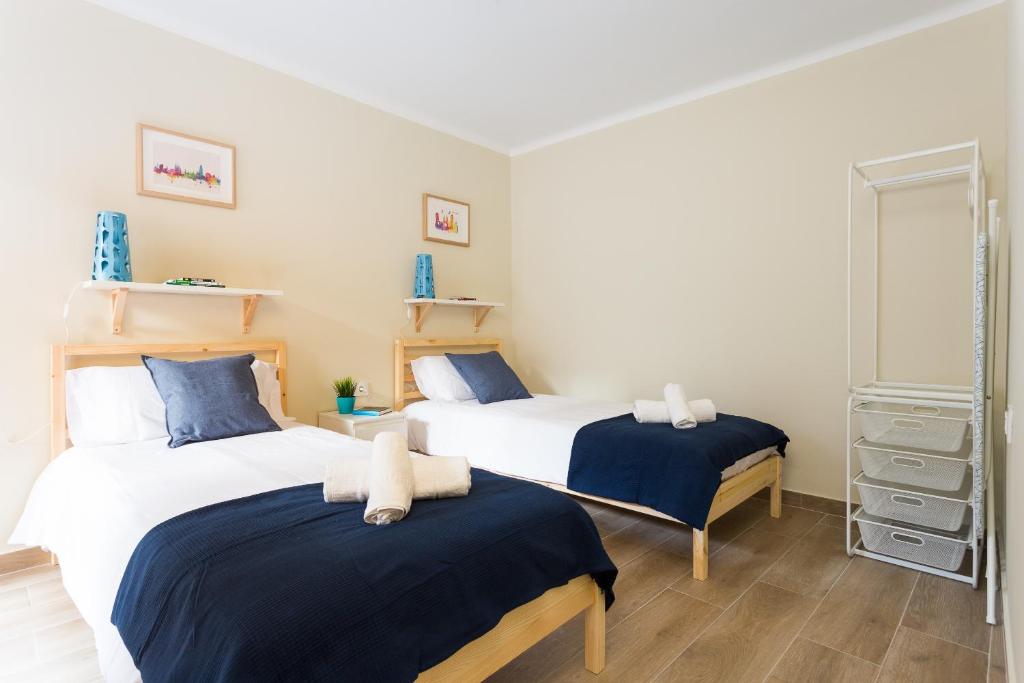2 Betten in einem blau-weißen Zimmer in der Unterkunft Brand New Apartment Near Camp Nou and Fira Barcelona in Hospitalet de Llobregat