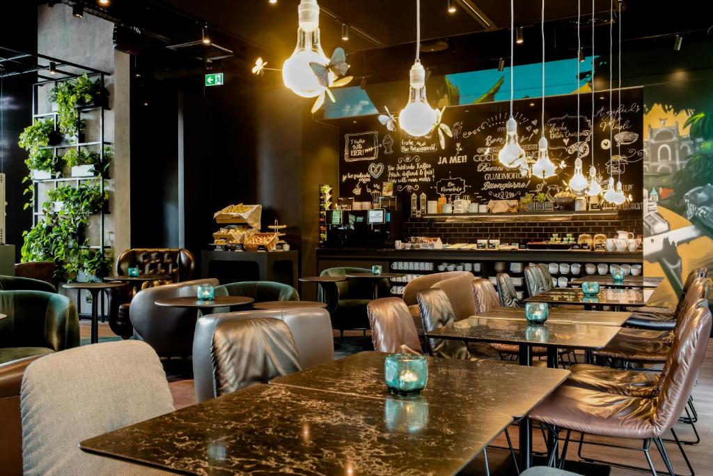 a restaurant with tables and chairs and a bar at Motel One München-East Side in Munich