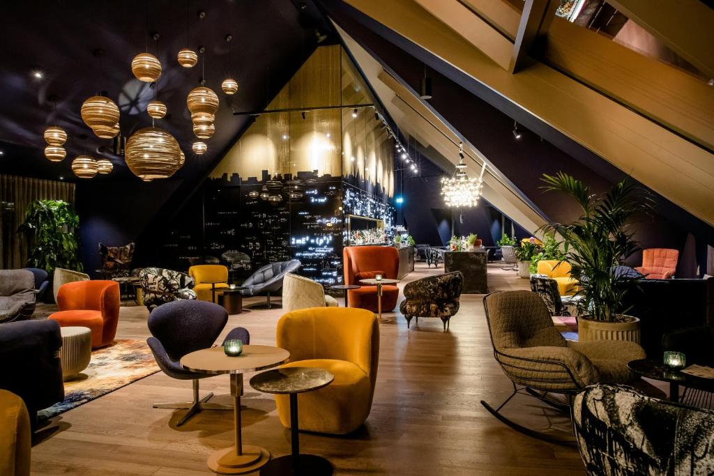 a lobby with chairs and tables and a bar at Motel One Ulm in Ulm