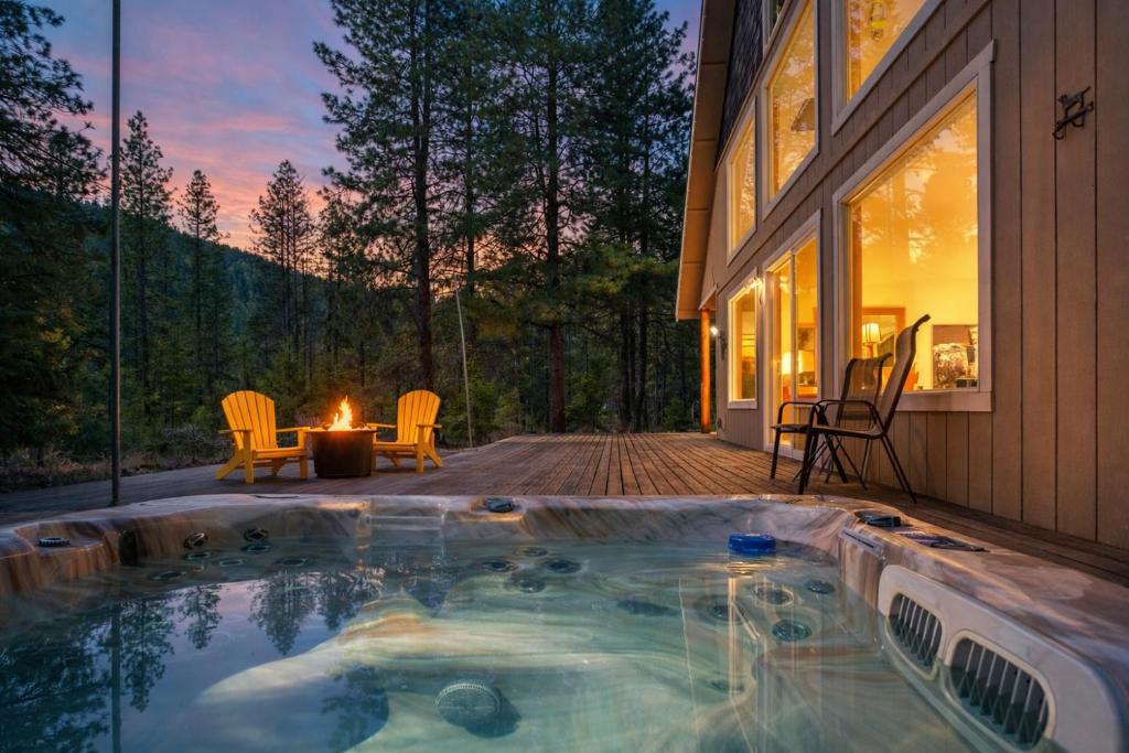 a hot tub on a deck next to a house at Pine Tree Cottage by NW Comfy Cabins in Leavenworth