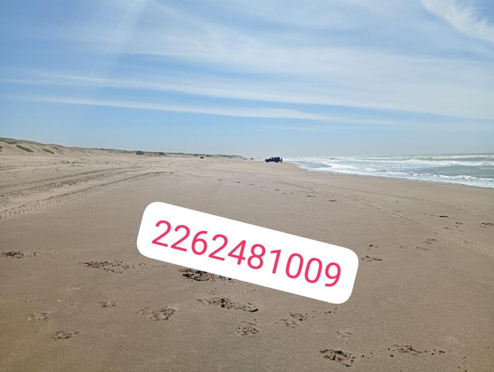 a beach sign on the sand on a beach at Cabaña in Necochea