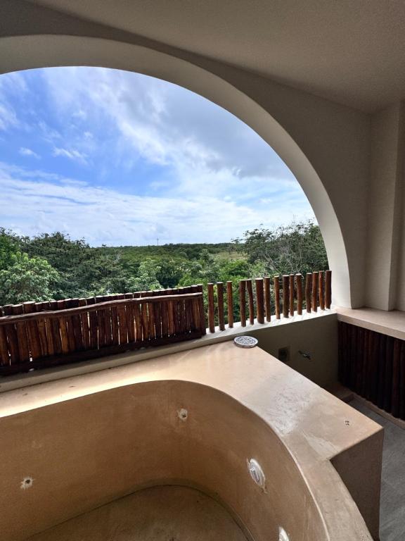 a room with a large window and a table with a view at Xiib Kaab Estudio con Jacuzzi in Tulum