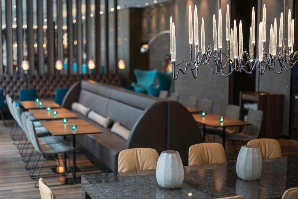 a restaurant with tables and chairs and chandeliers at Motel One Leipzig-Nikolaikirche in Leipzig
