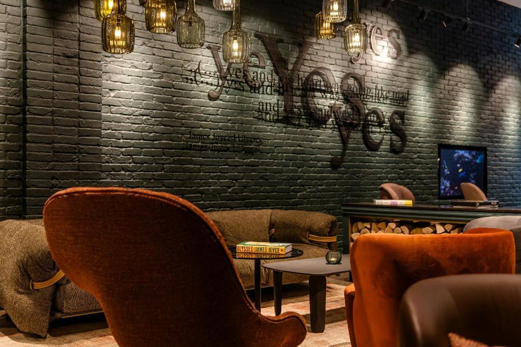a bar with chairs and a brick wall with graffiti at Motel One Dublin in Dublin