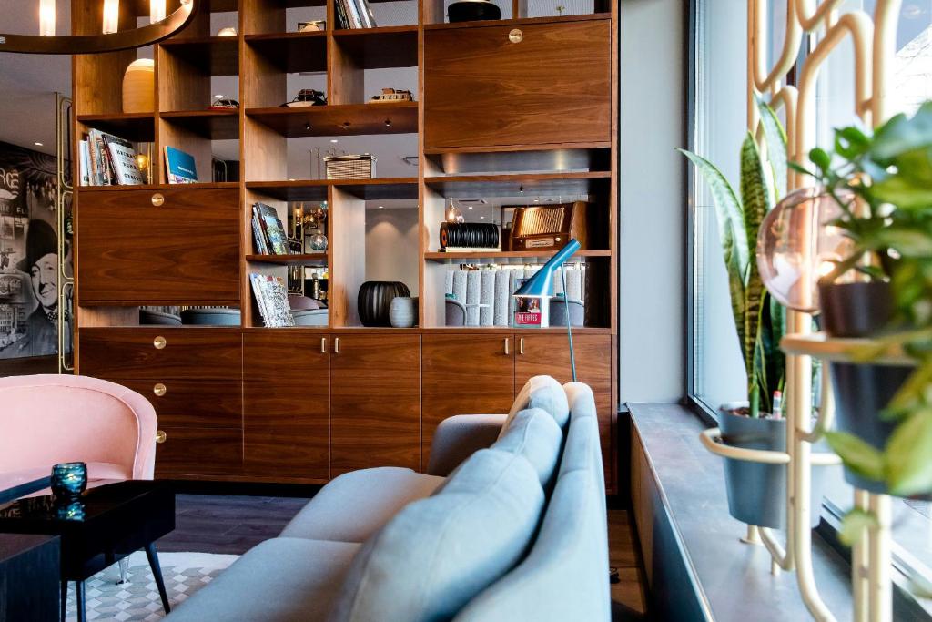 a living room with a couch and a book shelf at Motel One Essen in Essen
