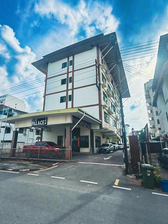 a large white building with a car parked in a parking lot at New Palace Inn in Miri
