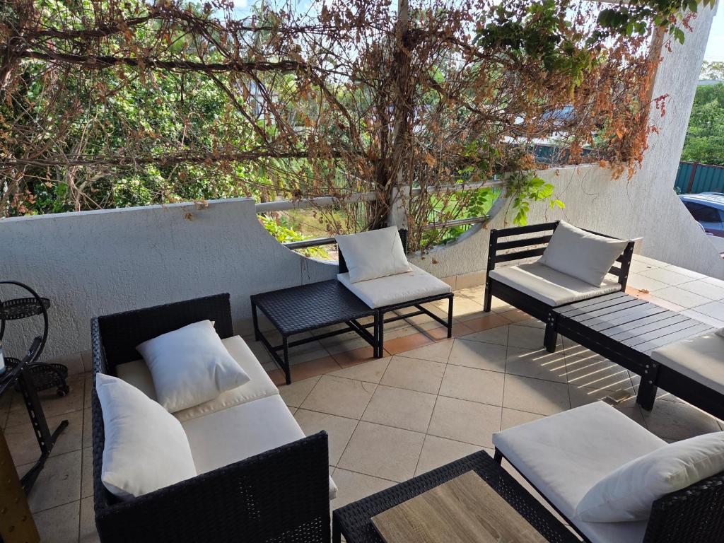 a patio with chairs and couches and a tree at BR Rooms in a Shared house in Kingston