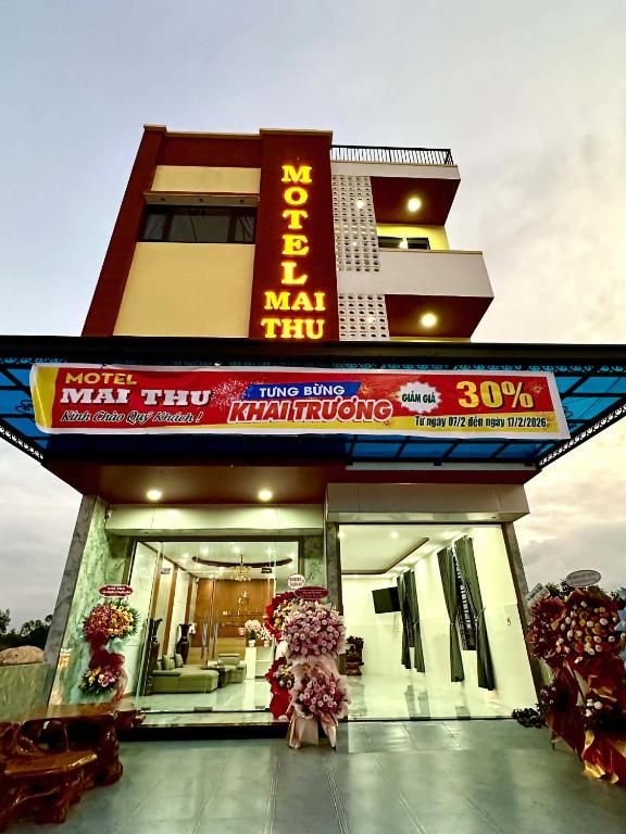 a woman standing in front of a building with umbrellas at Motel Mai Thu in Thăng Bình