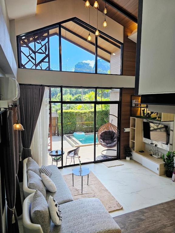 a living room with a couch and a large window at Ploy Mountain View Pool Villa in Ban Thai Thai