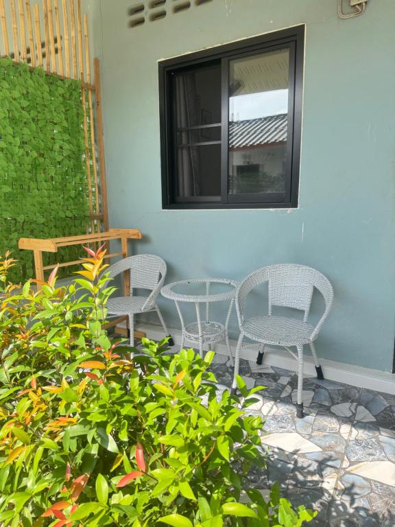 a patio with two chairs and a table and a window at Baan phuwamin in Ko Lanta