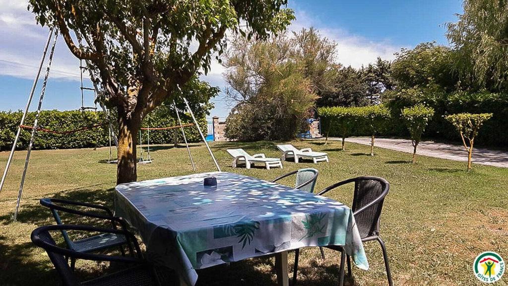 a table and chairs in a yard with a swing at Perets petit in Montégut-Lauragais