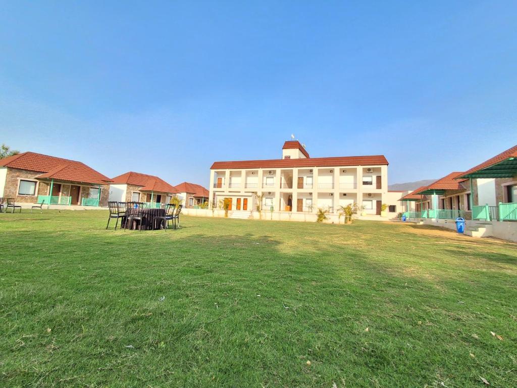 a large building with a grass field in front of it at Orchard Hills Resorts in Pushkar