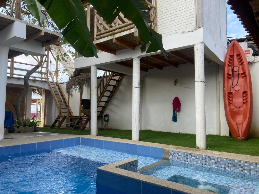 a house with a swimming pool and a surfboard on the wall at Villa en Salango con piscina in Salango