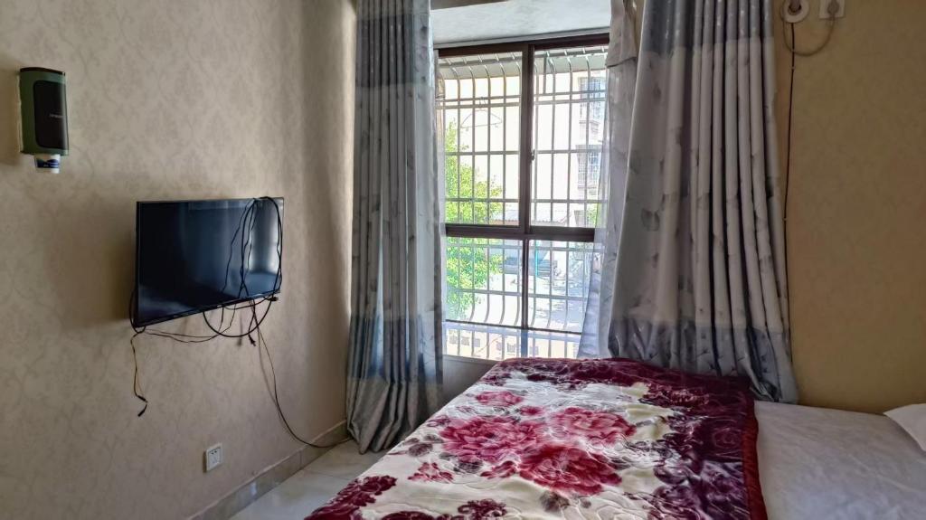 a bedroom with a bed and a tv and a window at 春栖客栈 in Chuanxingpu