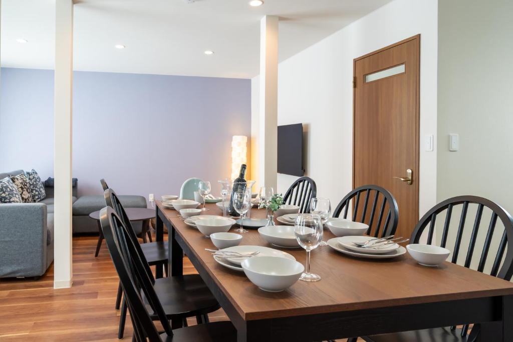 a long wooden table with bowls and plates on it at Villa Shigin in Nakafurano