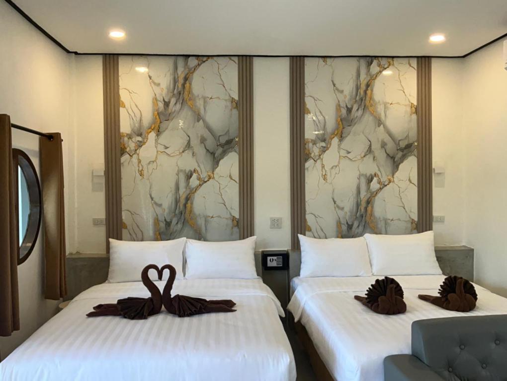 two beds in a hotel room with swans on them at Lanta Beautiful beach house 1 in Phra Ae beach