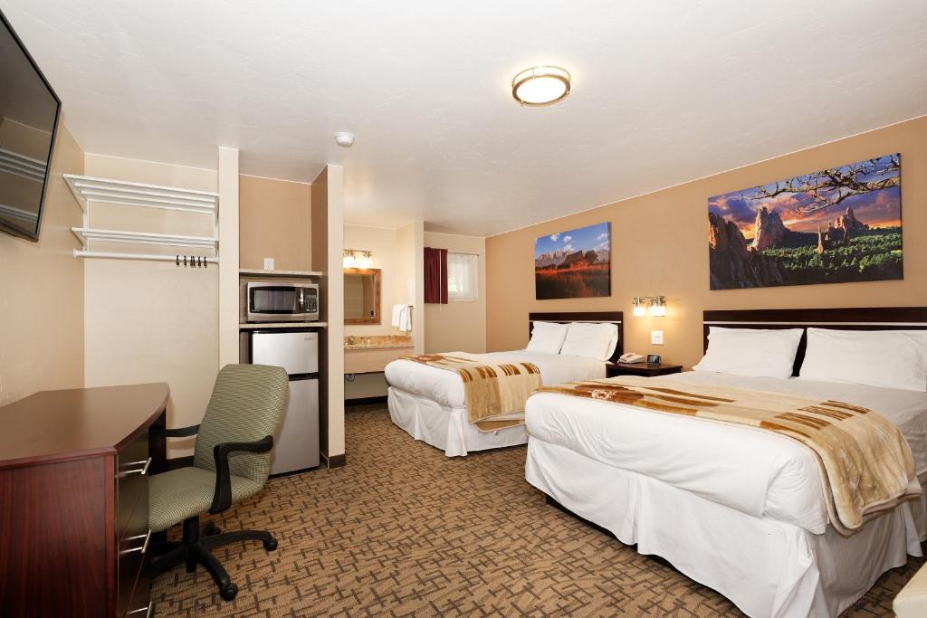 a hotel room with two beds and a desk at Glenwood Springs Inn in Glenwood Springs