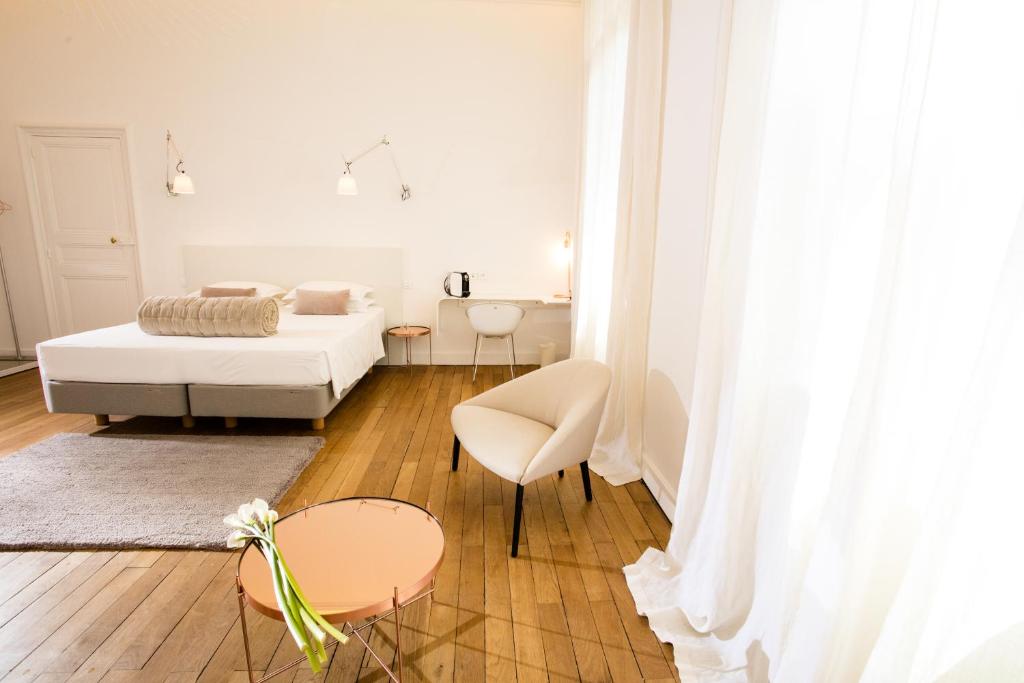 a white living room with a bed and a table at L'Hôtel Particulier Beziers in Béziers